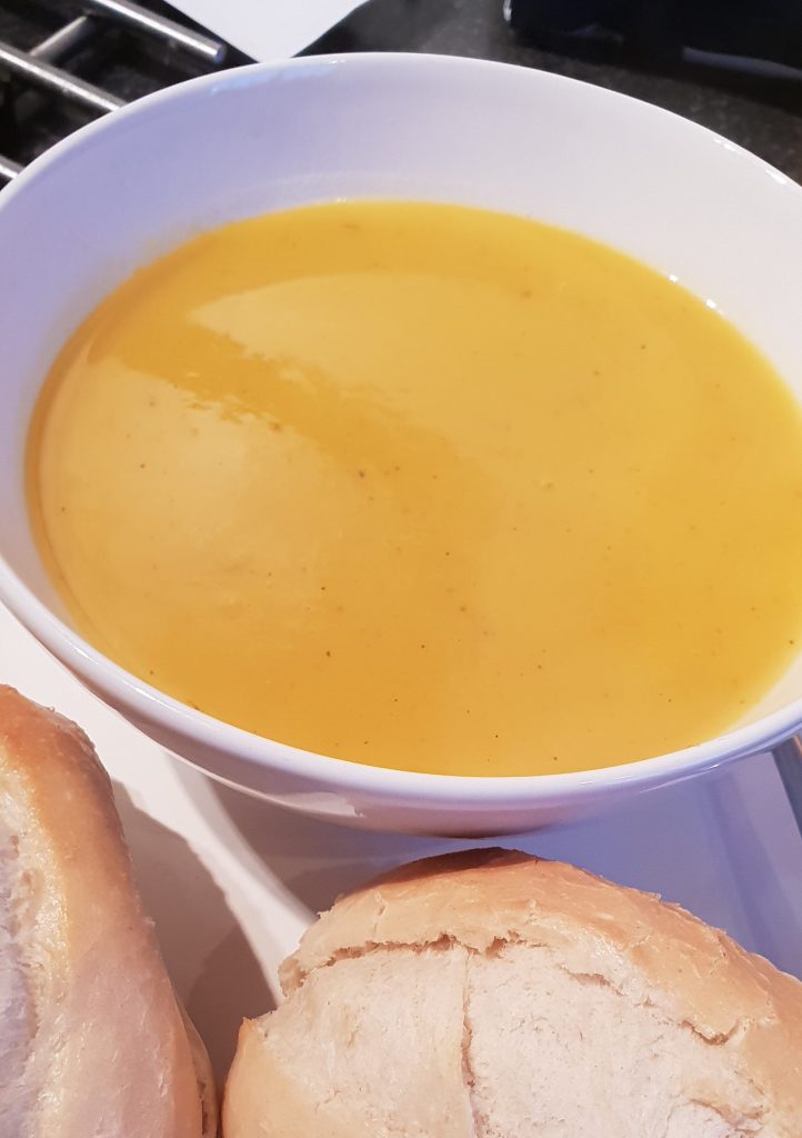 Bowl of butternut squash soup with bread rolls