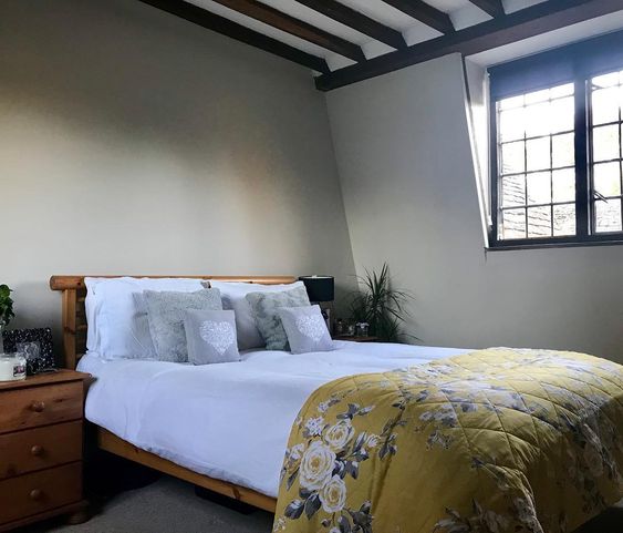 Image of a bed with white bedding and a yellow throw. Keep warm without turning the heating on