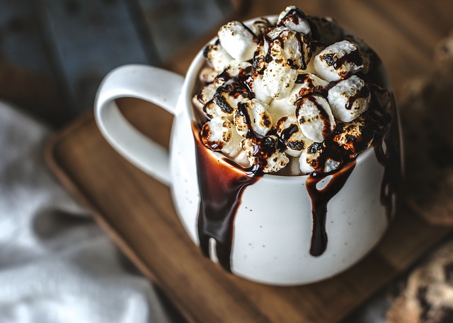 Full mug of hot chocolate with marshmallows and chocolate sauce dripping down the side