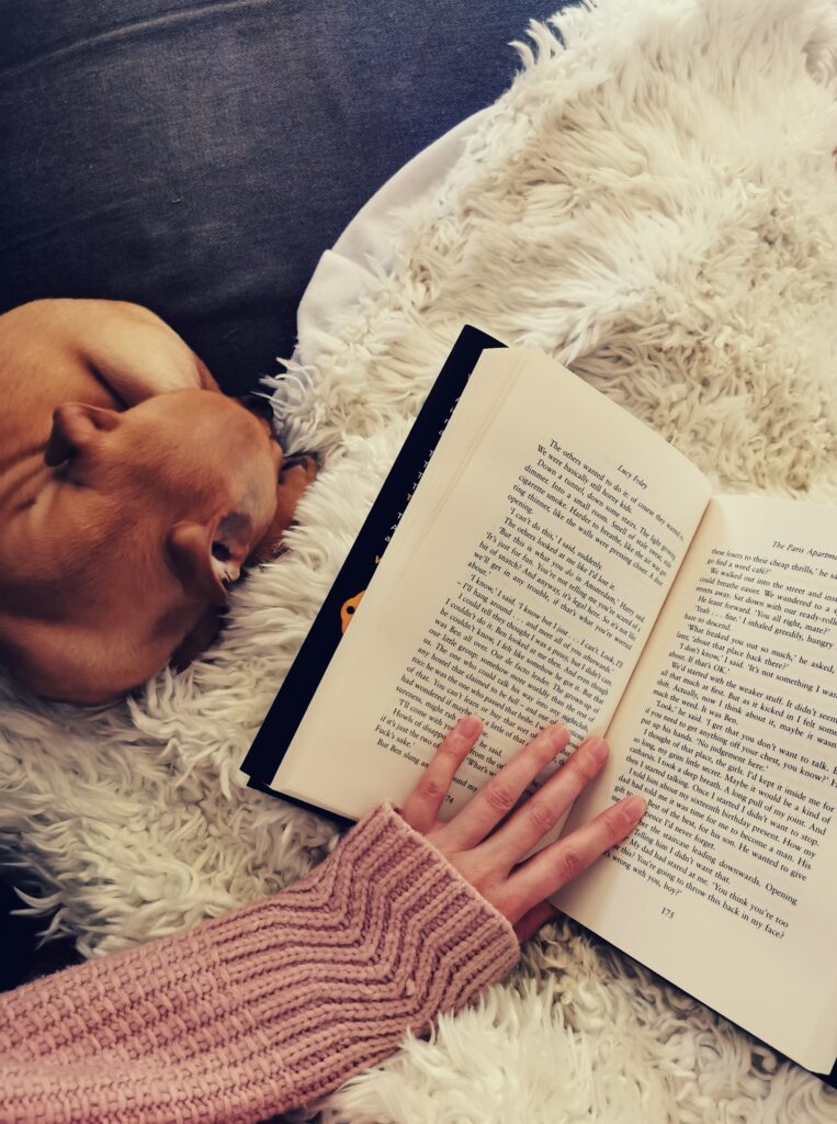 Open book on cosy blanket with sleeping puppy beside. 