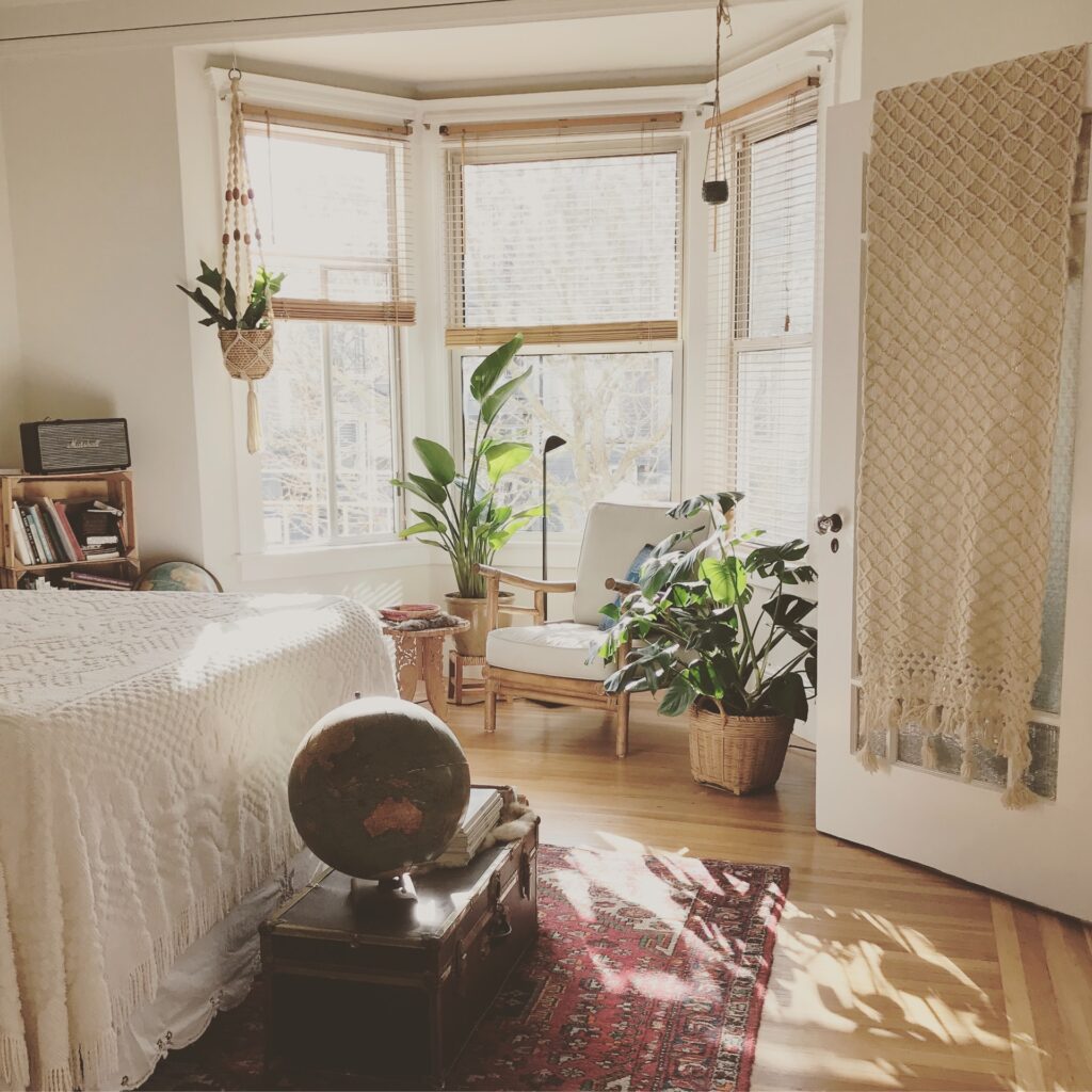 Neutral toned bedroom with chair and houseplants to create cosy corner