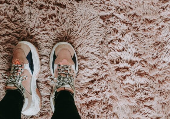 A pair of trainers on a pink tufted carpet