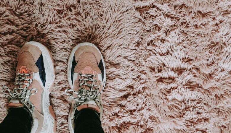 A pair of trainers on a pink tufted carpet